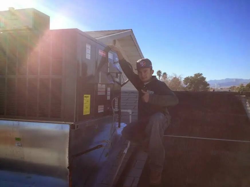 HVAC technician performing Heat Pump Repair on a rooftop unit in Clinton